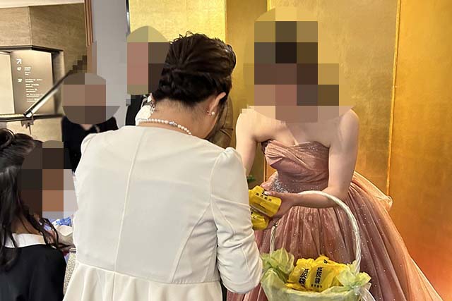 結婚式プチギフトに刻灰袋クッキーをゲストにお配りするご新婦様の写真